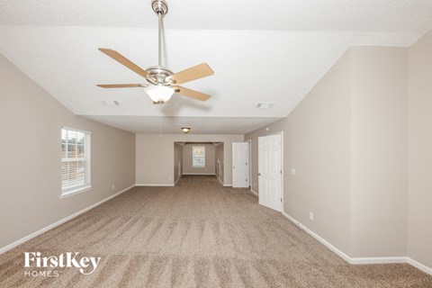 A spacious room with a fan and carpeted floor.