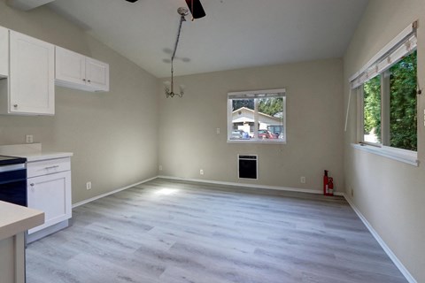 an empty living room with a window and a kitchen