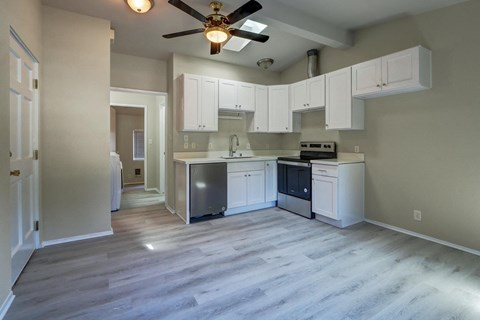 an empty kitchen with white cabinets and a ceiling fan
