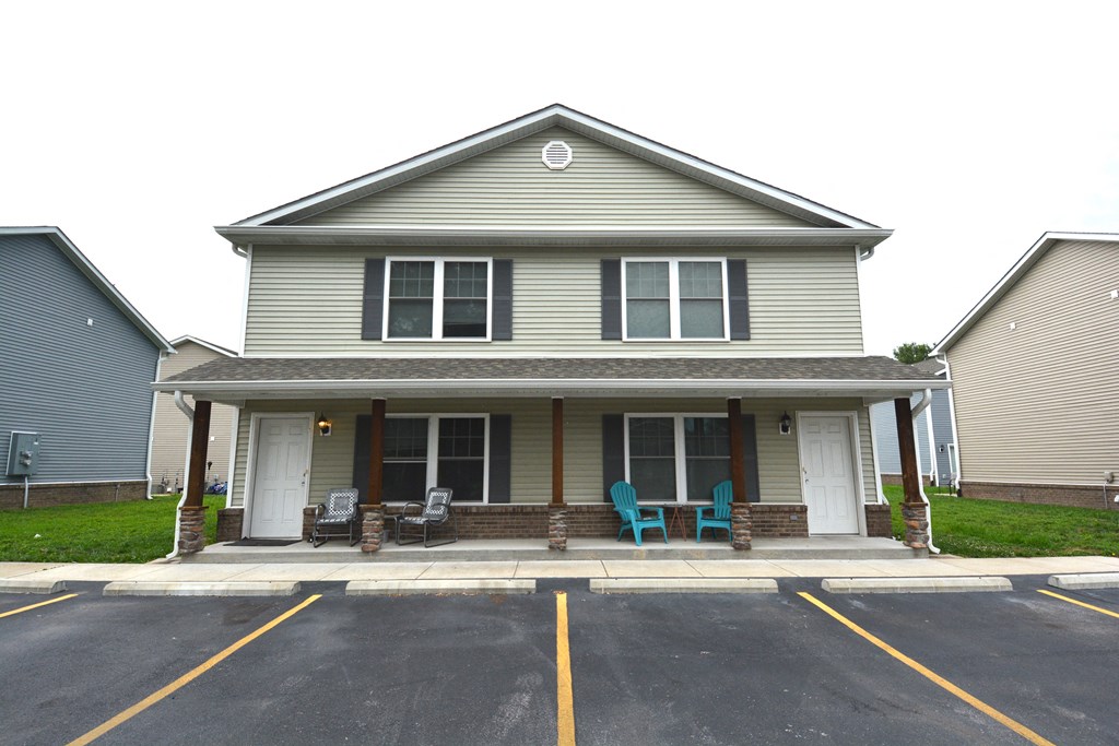 the front of a house with two rocking chairs on the porch