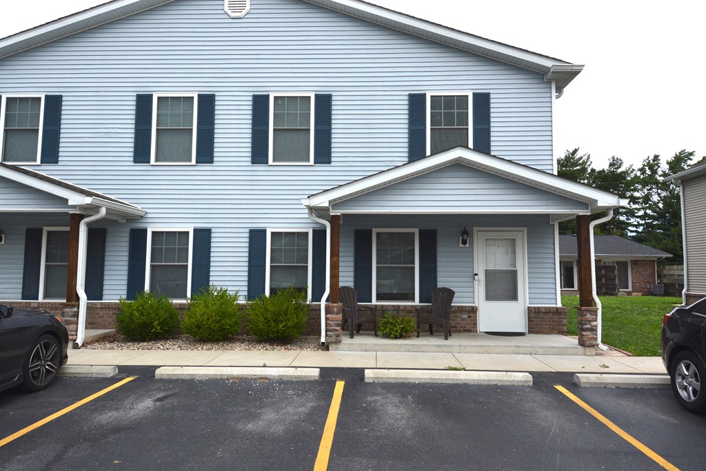 a blue house with blue shutters and a porch with chairs
