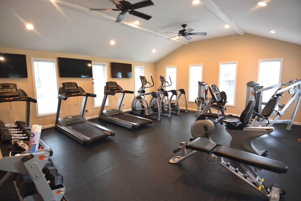 a gym with cardio equipment and flat screen tv