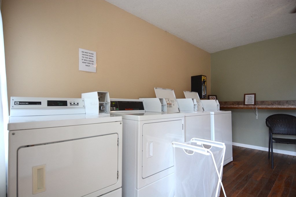a row of washers and dryers in a room with a wood floor and