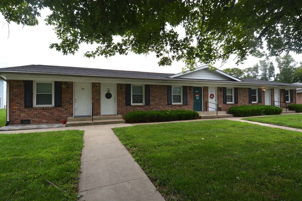 an old brick house with a sidewalk in front of it