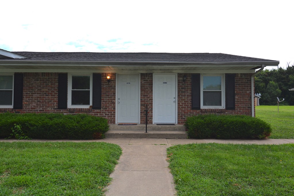 the front of a brick house with two white doors