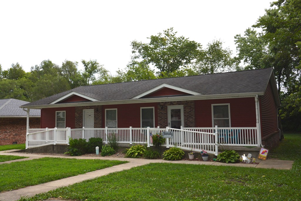 a red house with a porch and a white fence
