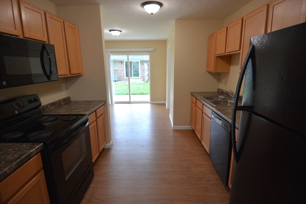 an empty kitchen with black appliances and wooden cabinets