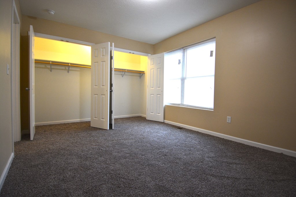 an empty bedroom with a closet and a window