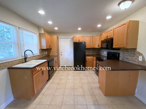A kitchen with brown cabinets and a black refrigerator.
