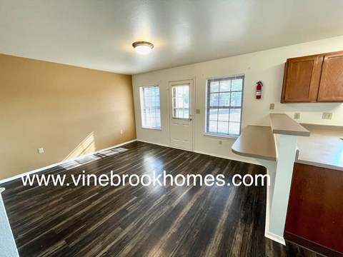 a kitchen and living room of a home with wood flooring and a table
