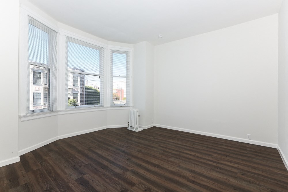 an empty living room with white walls and wood floors