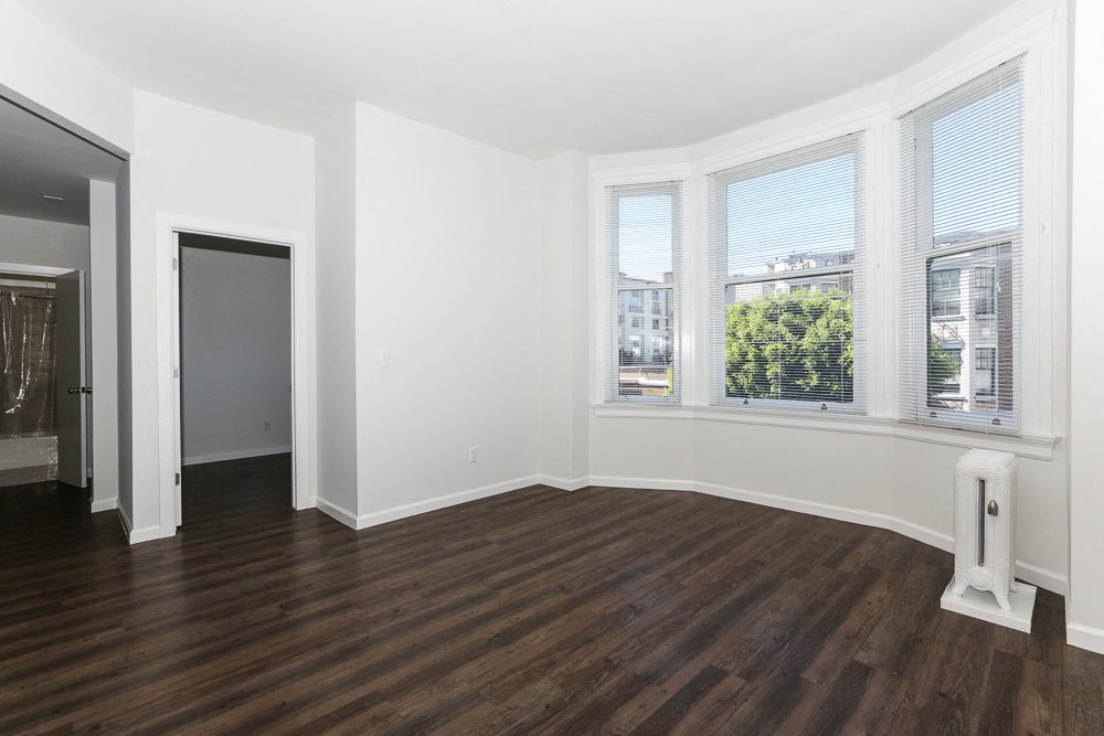 an empty living room with wood floors and a window