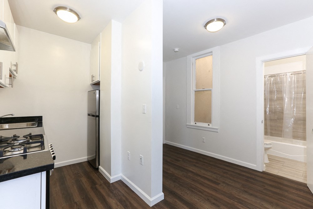 a renovated kitchen and living room with white walls and wood flooring
