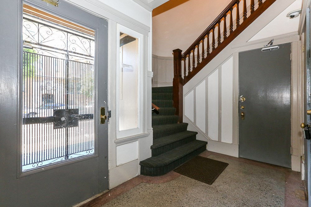 the entryway of a house with a staircase and a door with a metal door