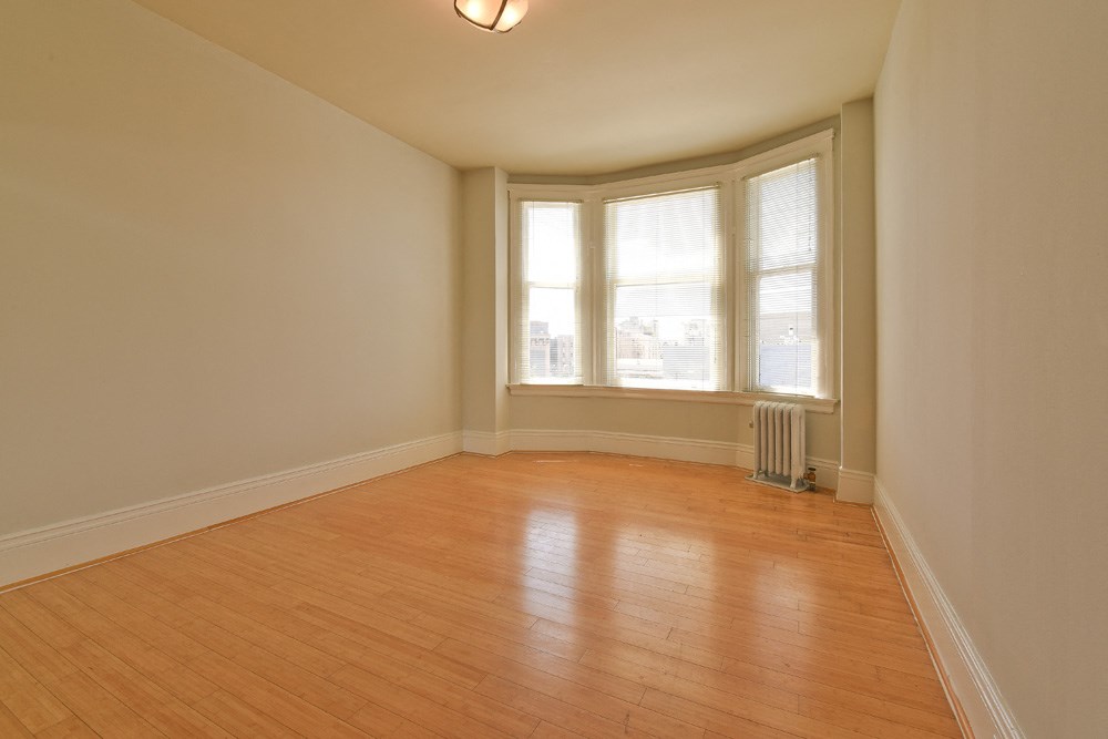 an empty living room with wood floors and a window