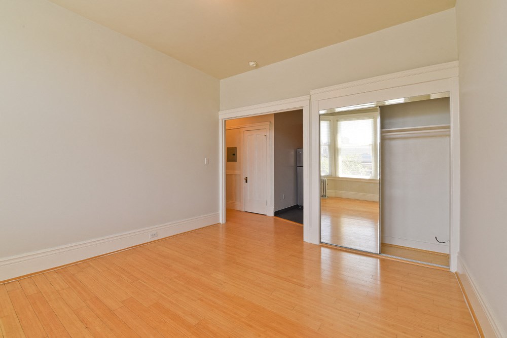 an empty living room with wood floors and a sliding glass door