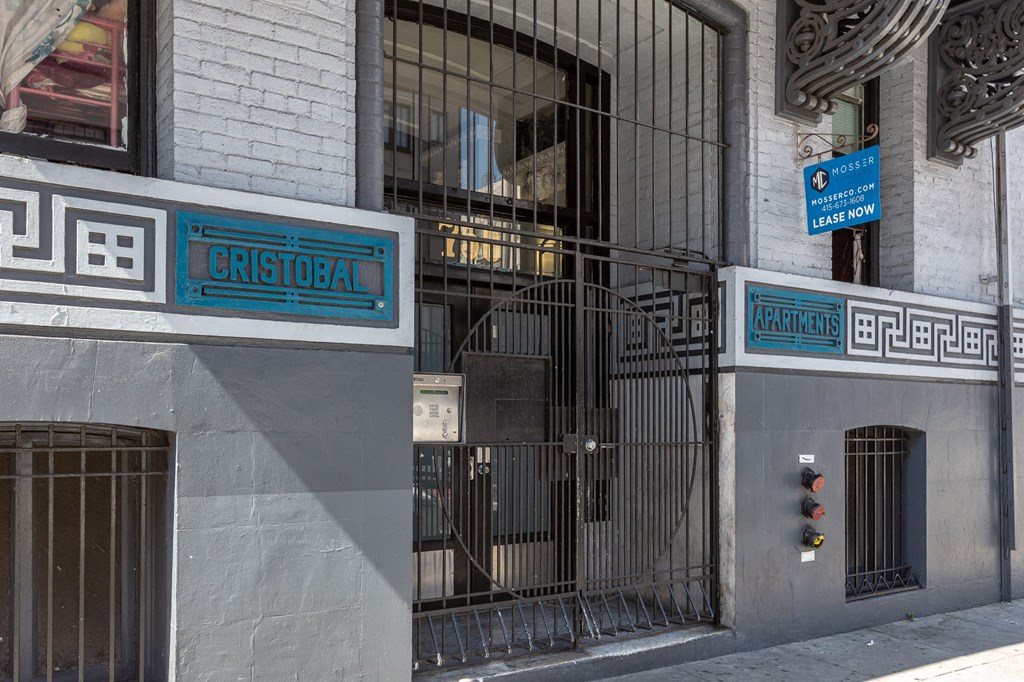 a building with a gate and a street sign on the side of it