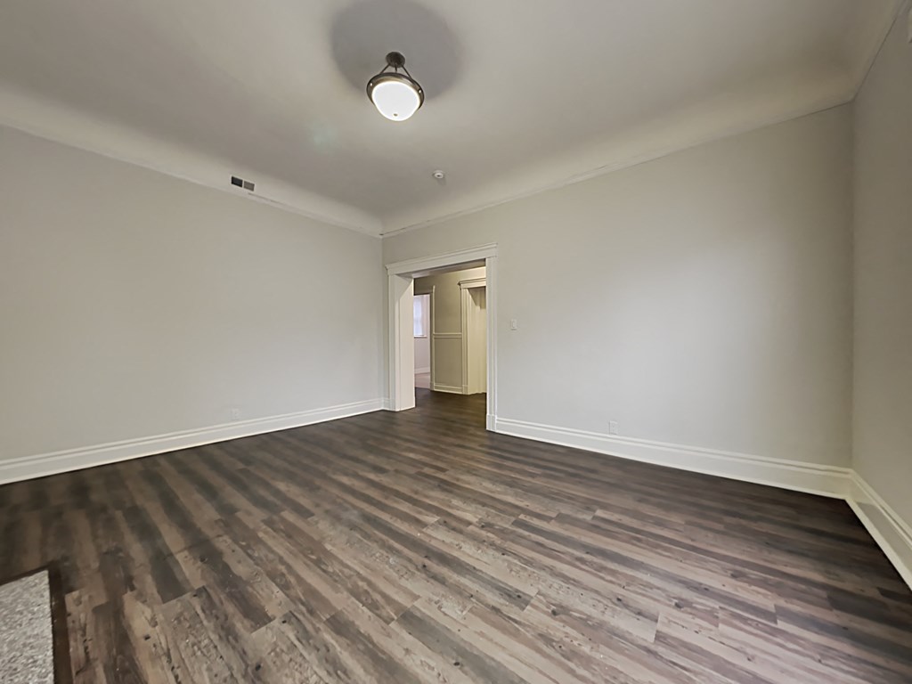 an empty living room with wood flooring and white walls