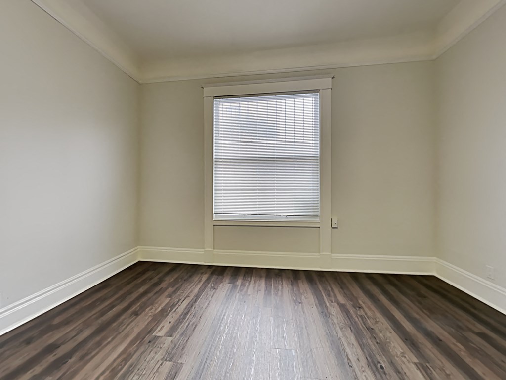 an empty room with wooden floors and a window