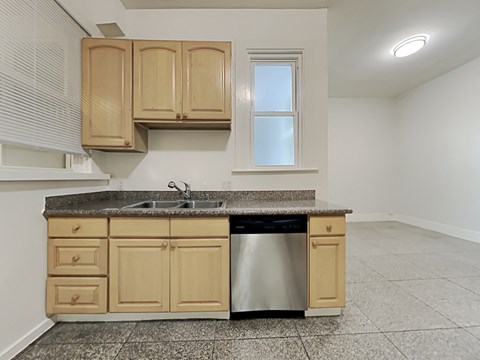 an empty kitchen with wooden cabinets and a stainless steel dishwasher