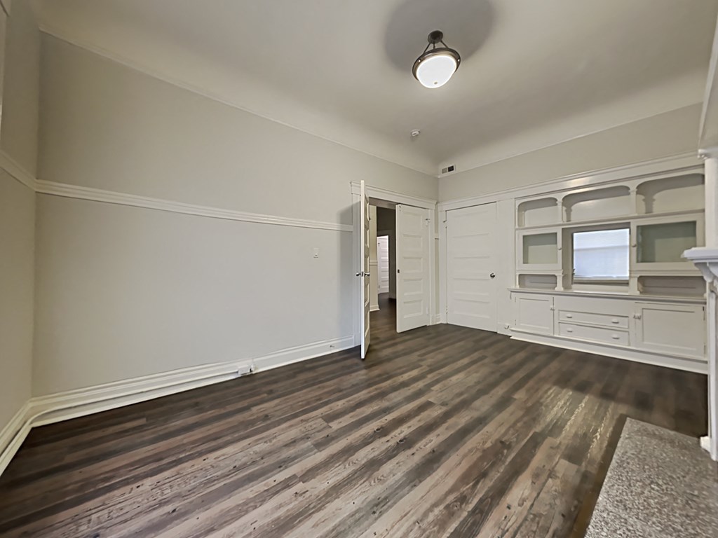 an empty living room with wood flooring and white walls