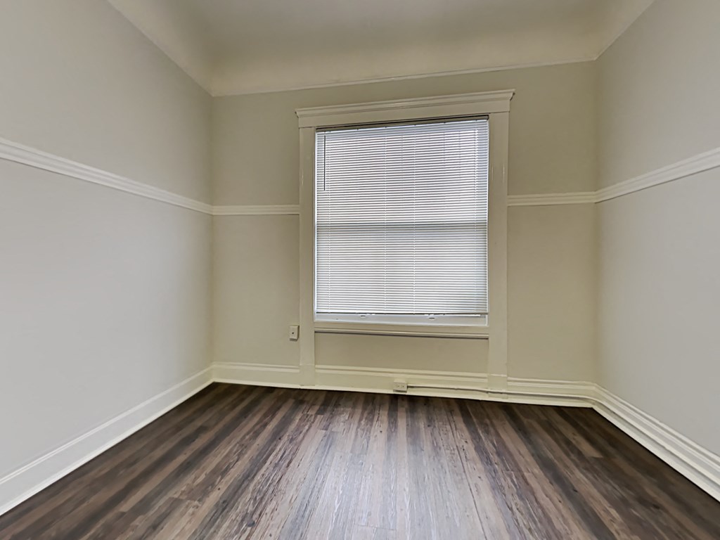 an empty room with wooden floors and a window