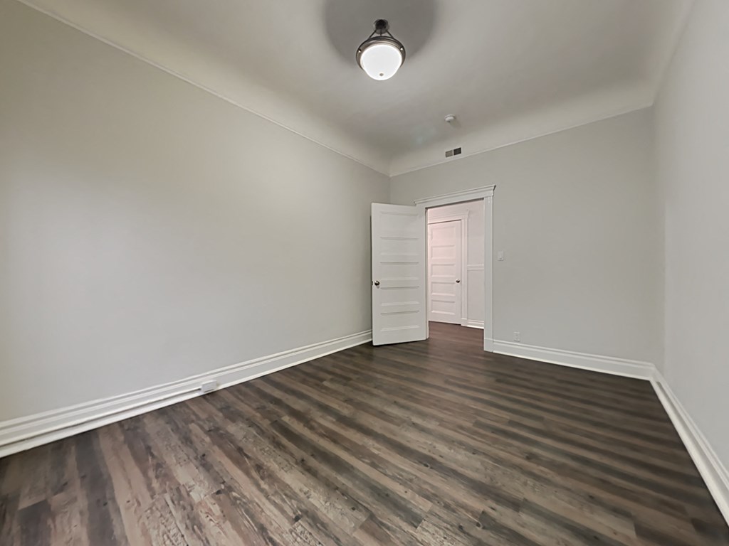 an empty living room with wood flooring and white walls