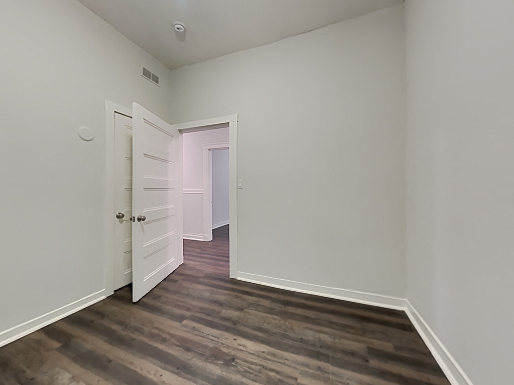 an empty bedroom with white walls and wood flooring