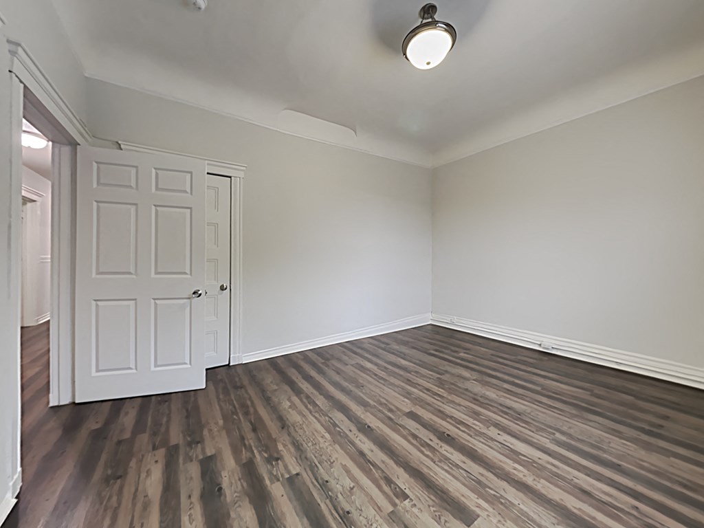 an empty living room with wood flooring and a white door