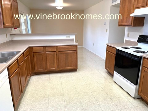 A kitchen with wooden cabinets and a white stove top oven.