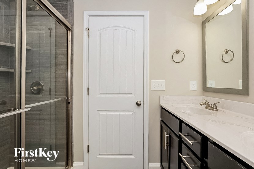 a bathroom with a shower and a sink and a white door