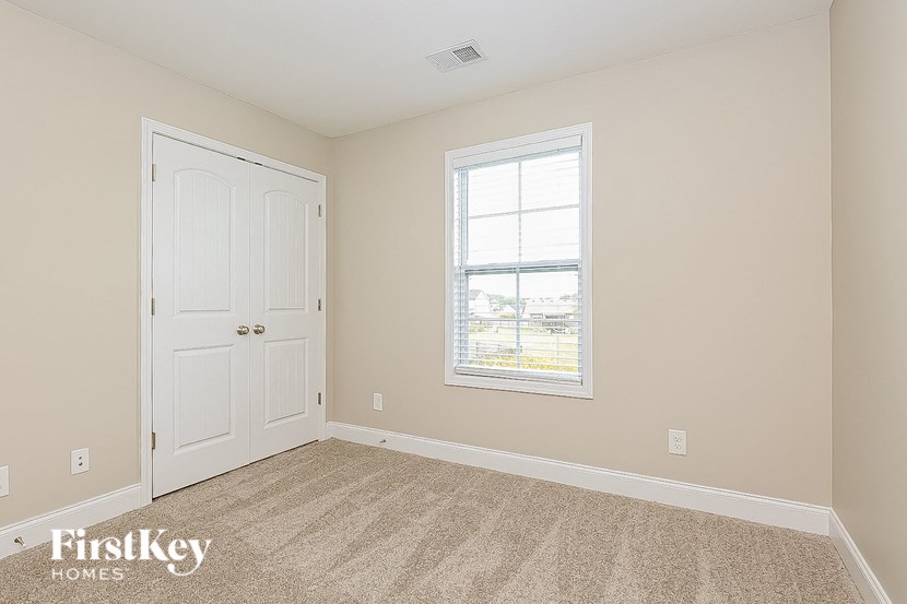 a bedroom with a door and a window and a carpeted floor