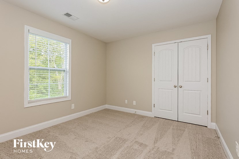 a bedroom with white doors and carpet and a window