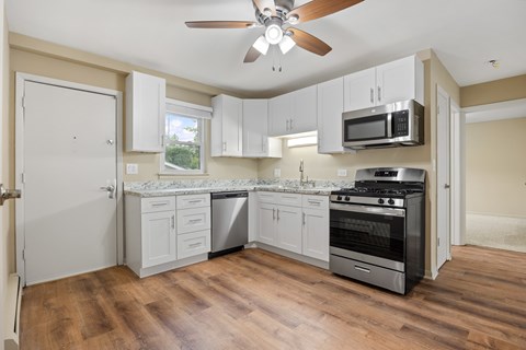 a kitchen with white cabinets and stainless steel appliances and a ceiling fan