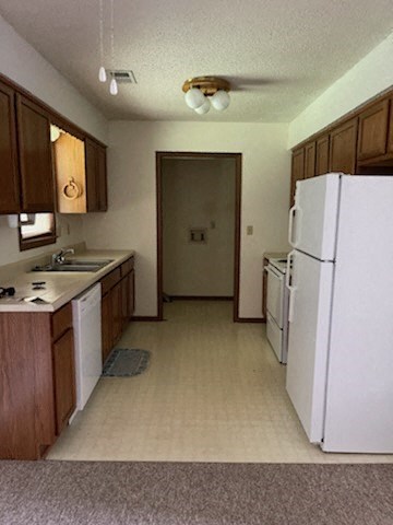 a kitchen with a white refrigerator and a sink
