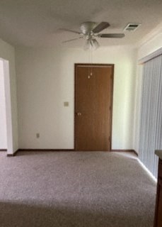 an empty living room with a ceiling fan and a door