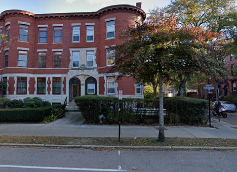 a red brick building with a tree in front of it