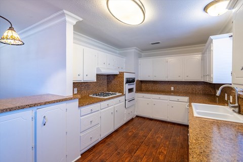 a kitchen with white cabinets and granite counter tops and a sink