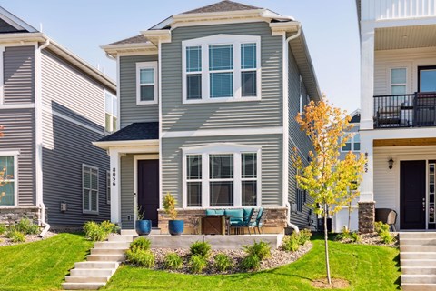 a gray house with a patio and a table and chairs in the yard