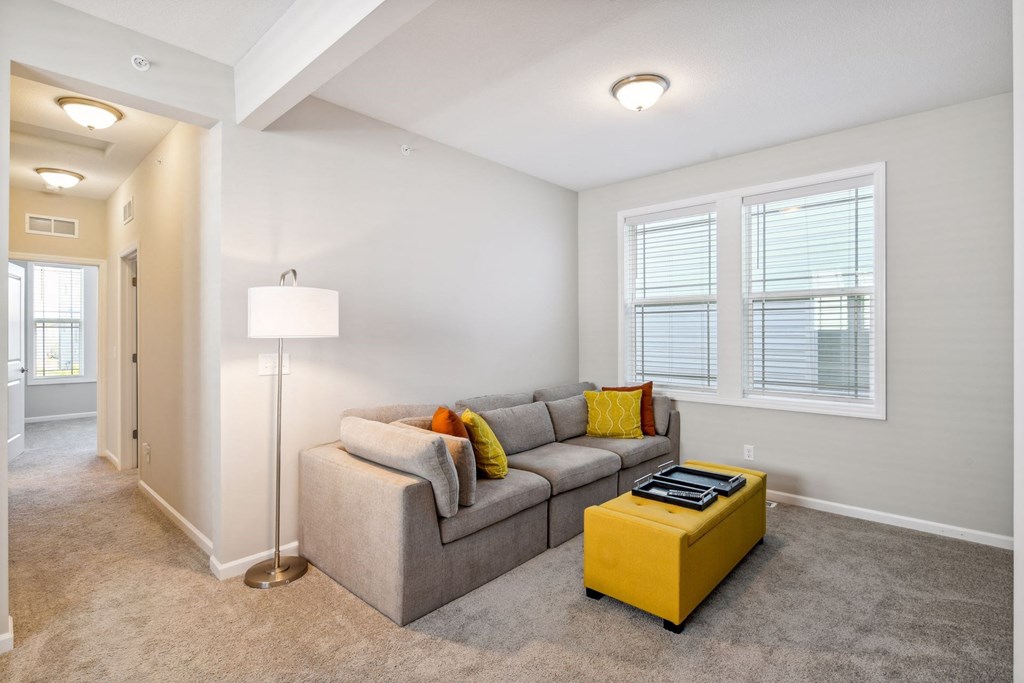 a living room with a couch and a yellow ottoman