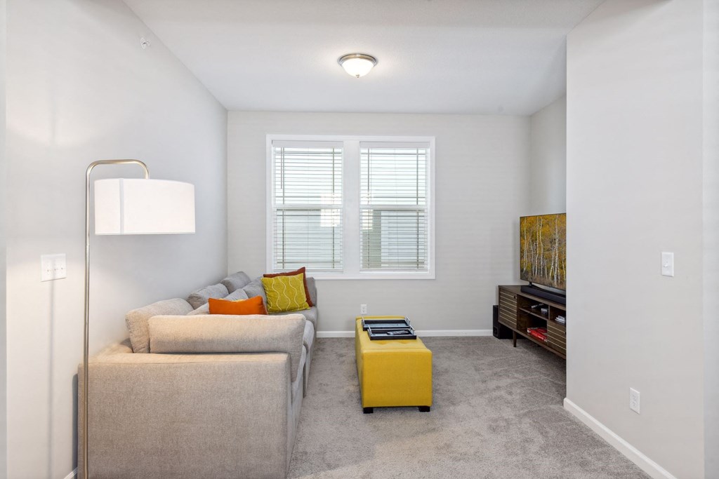 a living room with a couch and a yellow ottoman