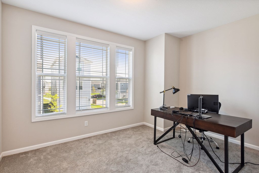 an office with windows and a desk with a computer