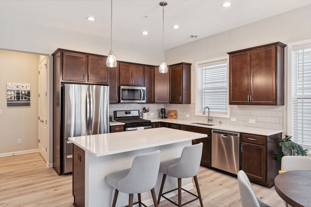 a kitchen with a large island and a stainless steel refrigerator