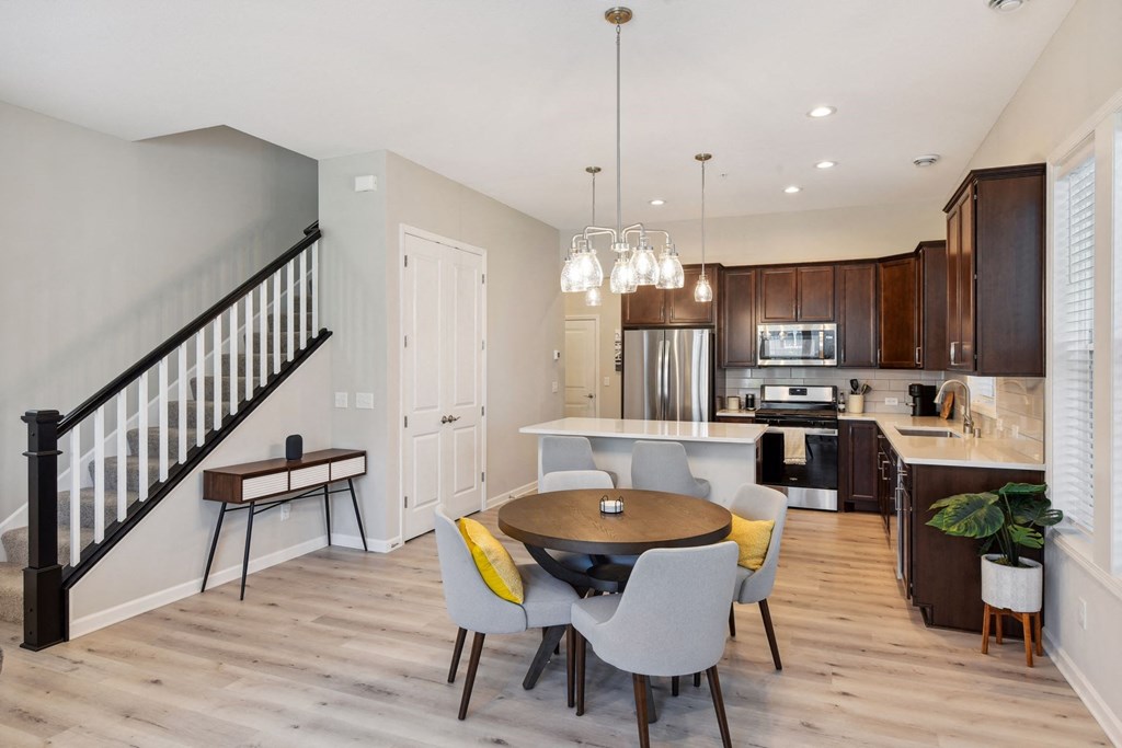 a dining room with a table and chairs and a kitchen with a staircase