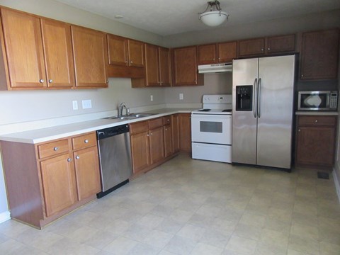 A kitchen with wooden cabinets and a white fridge.