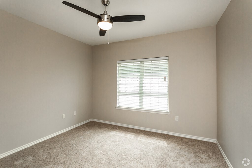 an empty bedroom with a ceiling fan and a window
