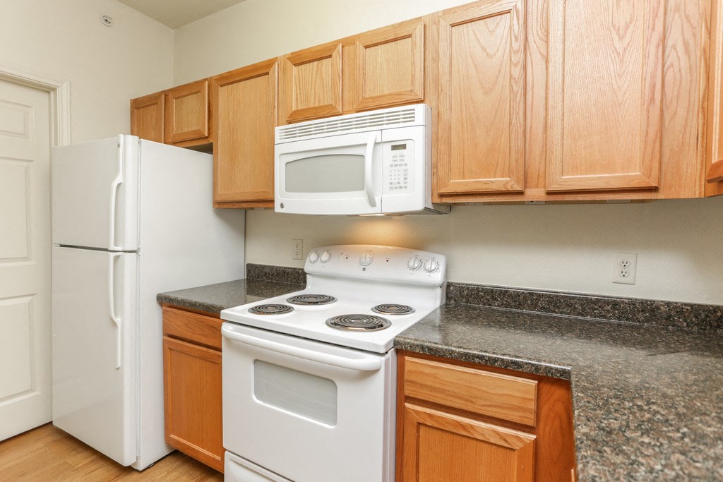 a kitchen with white appliances and granite counter tops and wooden cabinets