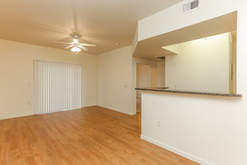 an empty living room with wood flooring and a ceiling fan