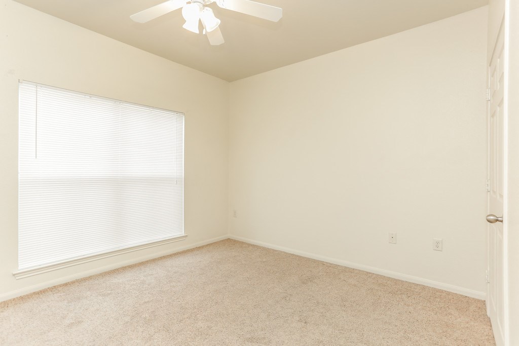 an empty bedroom with a large window and a ceiling fan
