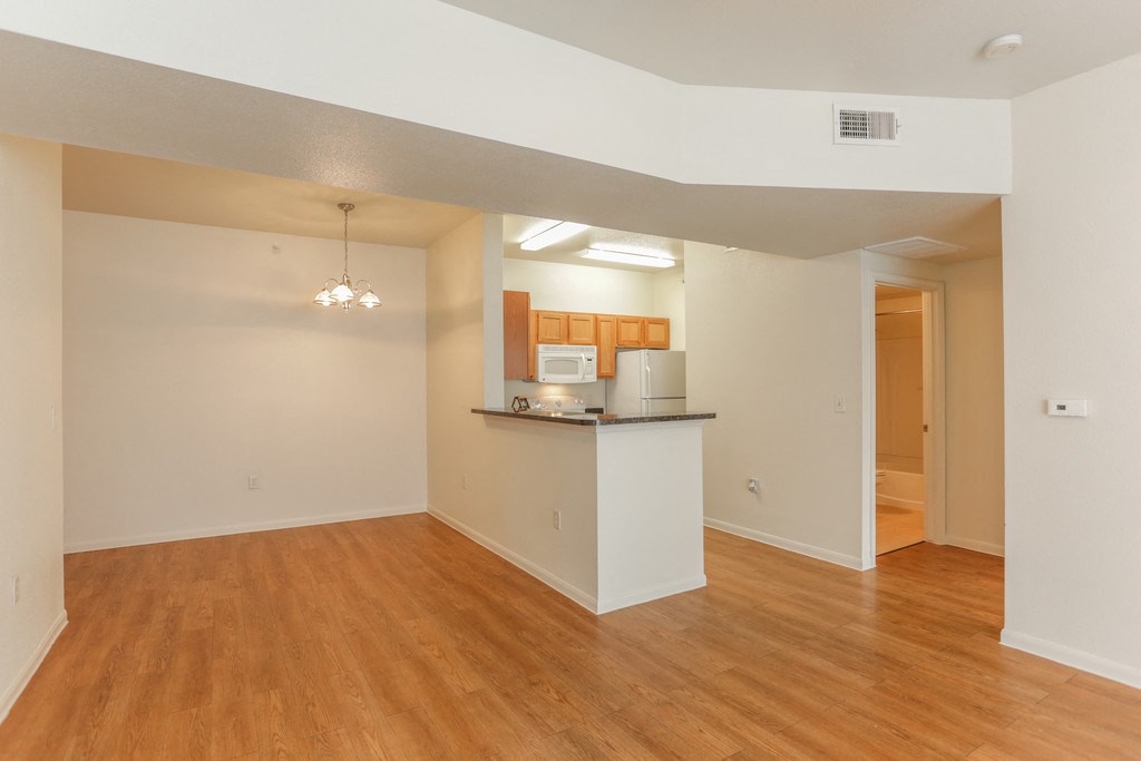 the spacious living room and kitchen of an empty apartment